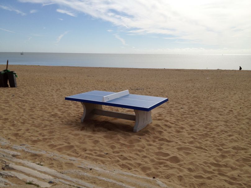 Betonnen pingpongtafel op strand bij zee